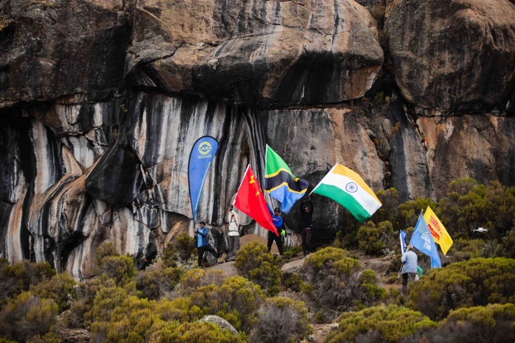 Hikers with flags from various countries at a scenic rocky mountain landscape.